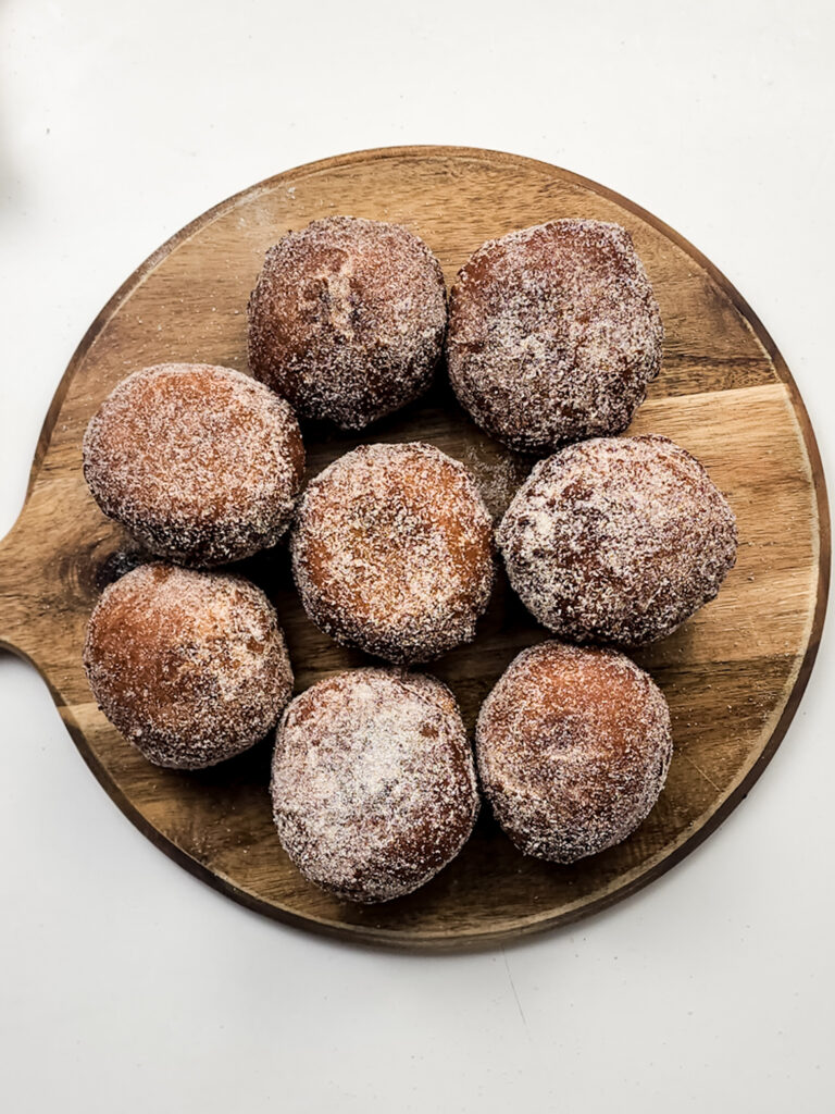 These apple pie doughnuts combine a spiced apple cider batter, homemade apple pie filling, and a cinnamon-sugar coating.