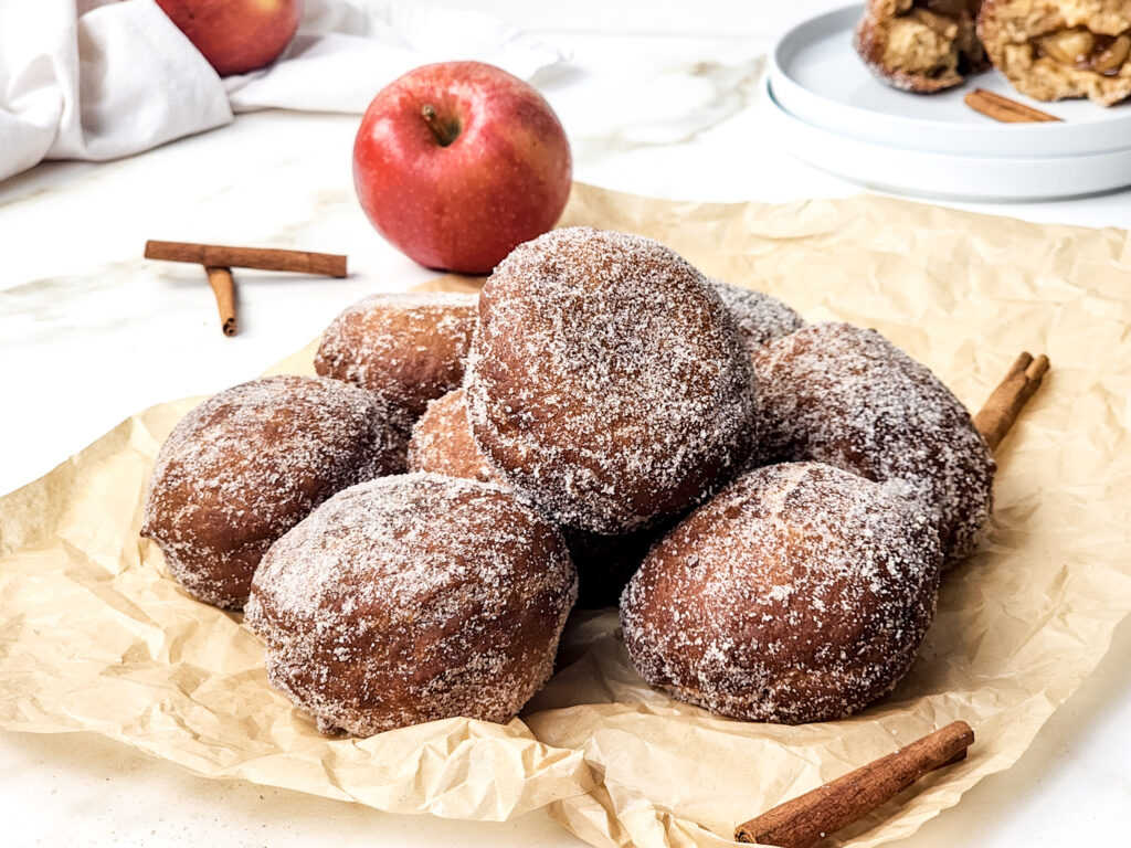 These apple pie doughnuts combine a spiced apple cider batter, homemade apple pie filling, and a cinnamon-sugar coating.