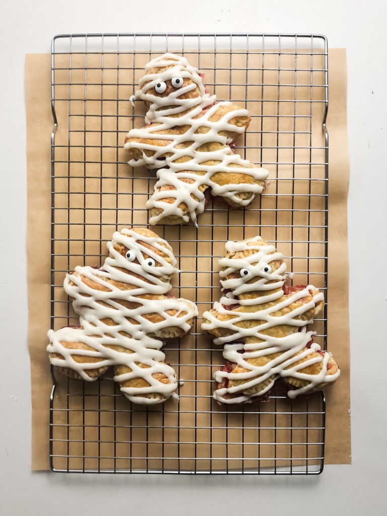 These Halloween Mummy Pop Tarts are spooky, easy, and delicious—flaky pastry, sweet jam, icing, and edible eyes!